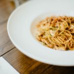 Angel Hair Pasta Topped with Pan Fried Chicken Pieces in a White Bowl
