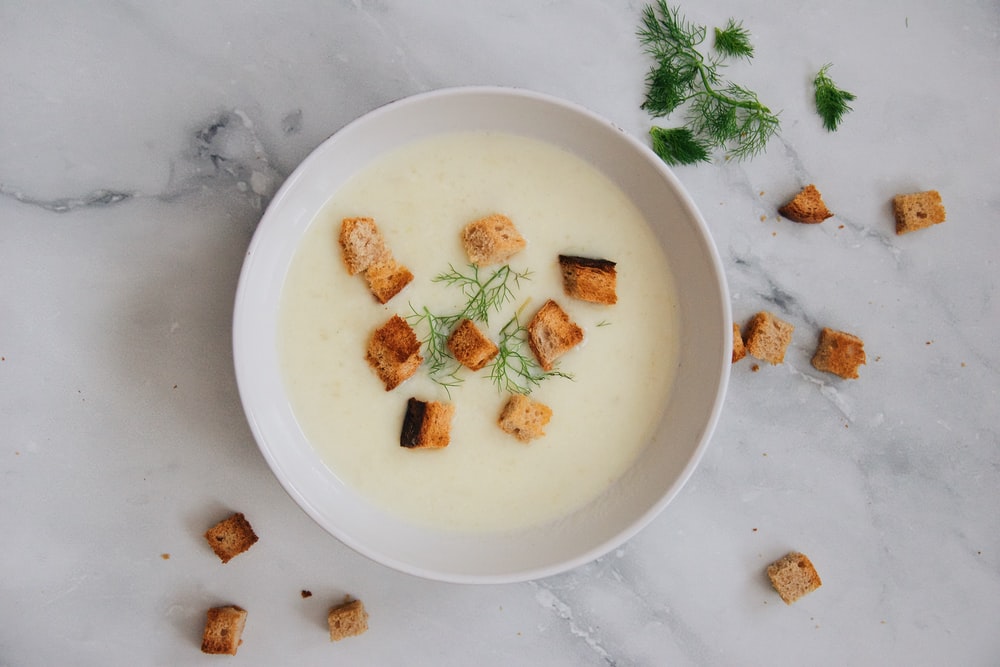 Potato-leek soup in a white porcelain bowl. Topped with croutons